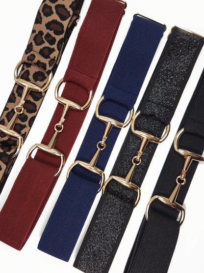 Assorted bit belts with gold buckles in multiple colors and prints for equestrian use.
